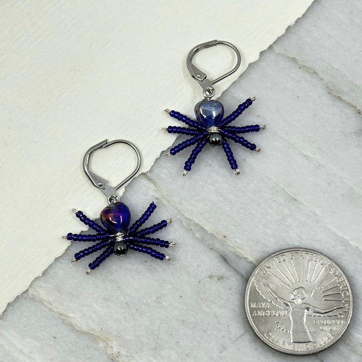 Pair of dark blue Spider Beaded Earrings with Stainless Steel Lever Backs, handmade in Montana USA by Aurum Shimmer, with scale