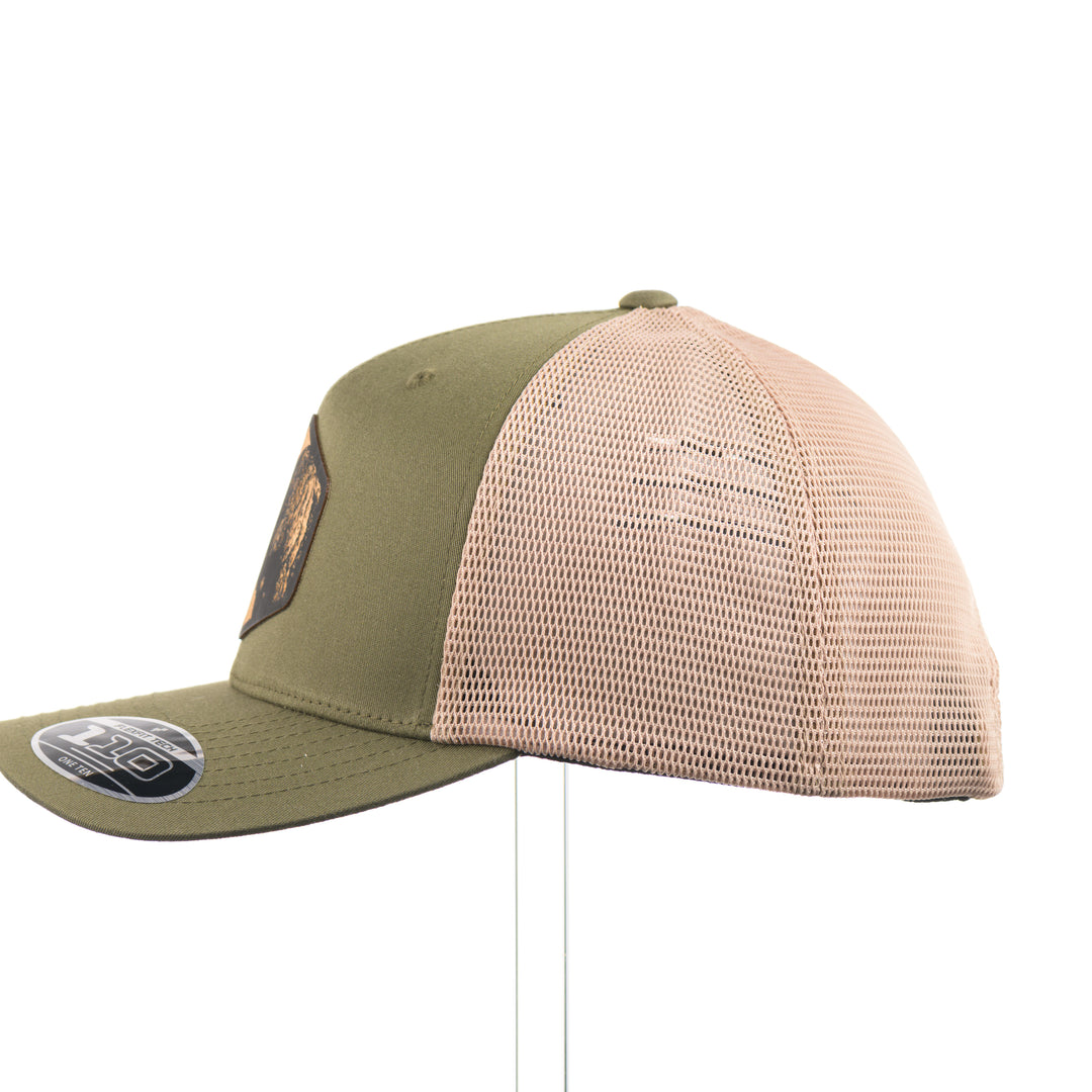 The side of an olive green and khaki mesh flexfit trucker hat with a bison flexwood hexagon patch.