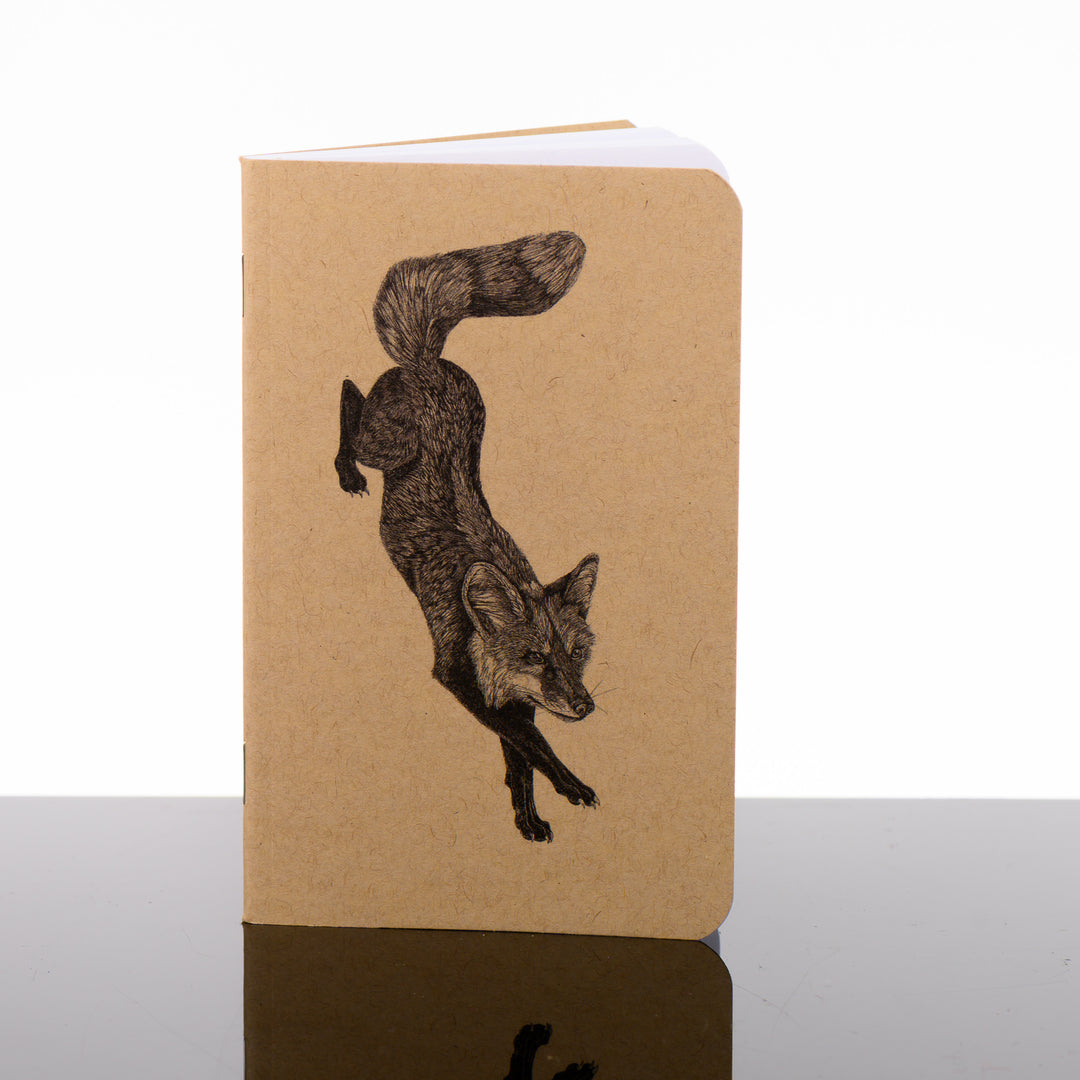 Fox Pocket Journal featuring black and white drawing by Montana artist Brittany Finch (a fox descending from a leap); blank journal with Kraft brown cover made in Montana, USA