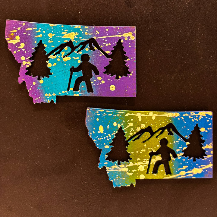A made in Montana state-shaped cut-out with silhouettes of hikers embedded in it and a strong back magnet.