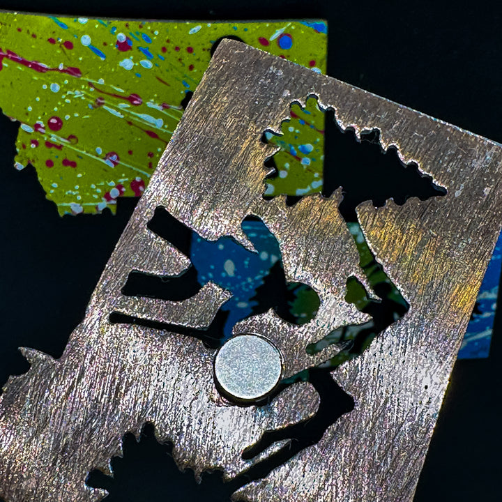 A made in Montana state-shaped cut-out with silhouettes of hikers embedded in it and a strong back magnet.
