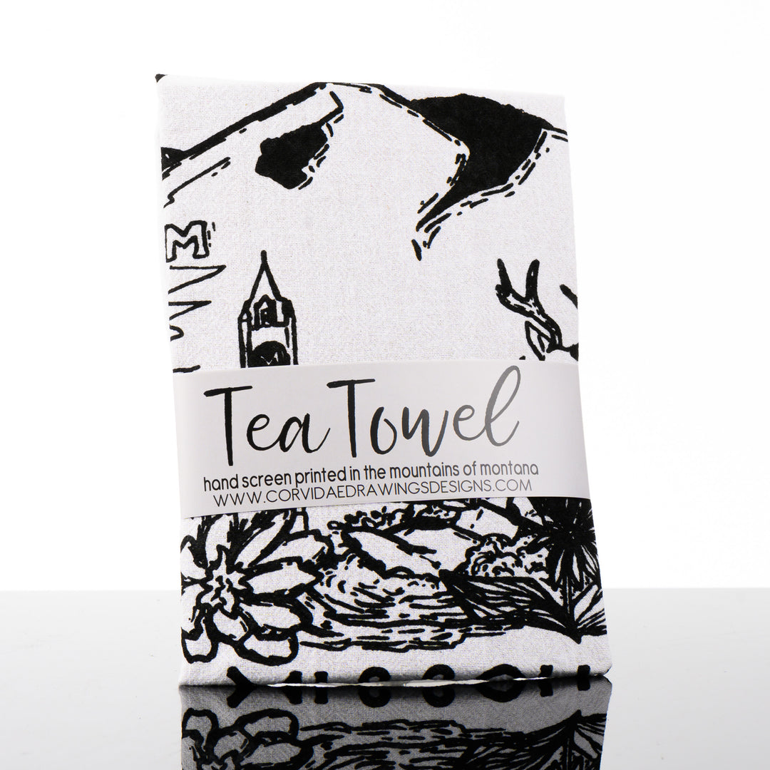 This made in Montana printed tea towel by Corvidae features a black and white drawing of Mount Sentinel, the M, the clock tower, bitterroots and a deer in Missoula Valley.