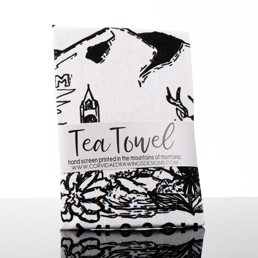 This made in Montana printed tea towel by Corvidae features a black and white drawing of Mount Sentinel, the M, the clock tower, bitterroots and a deer in Missoula Valley.