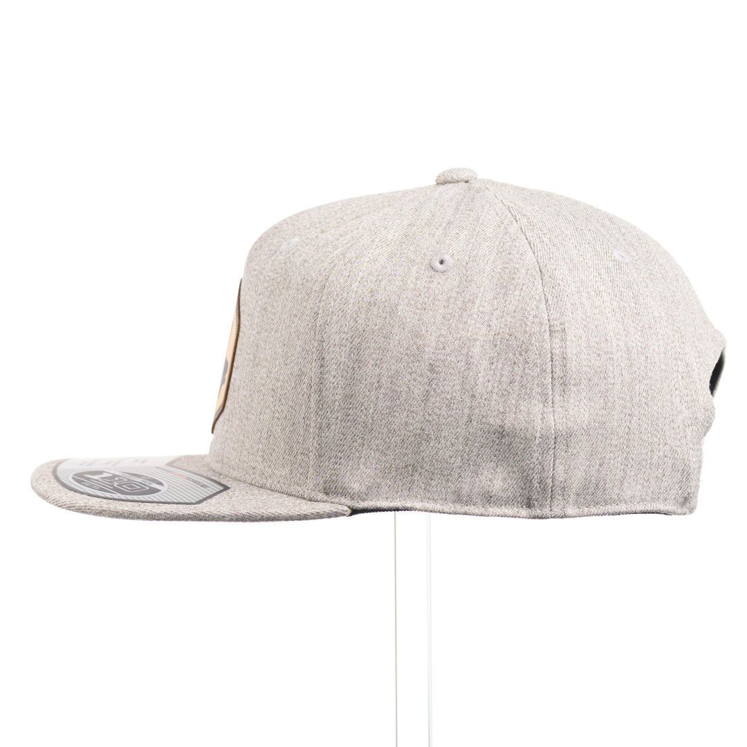 The side of a heather grey flexfit flat bill hat with a hexagon elk silhouette flexwood patch.