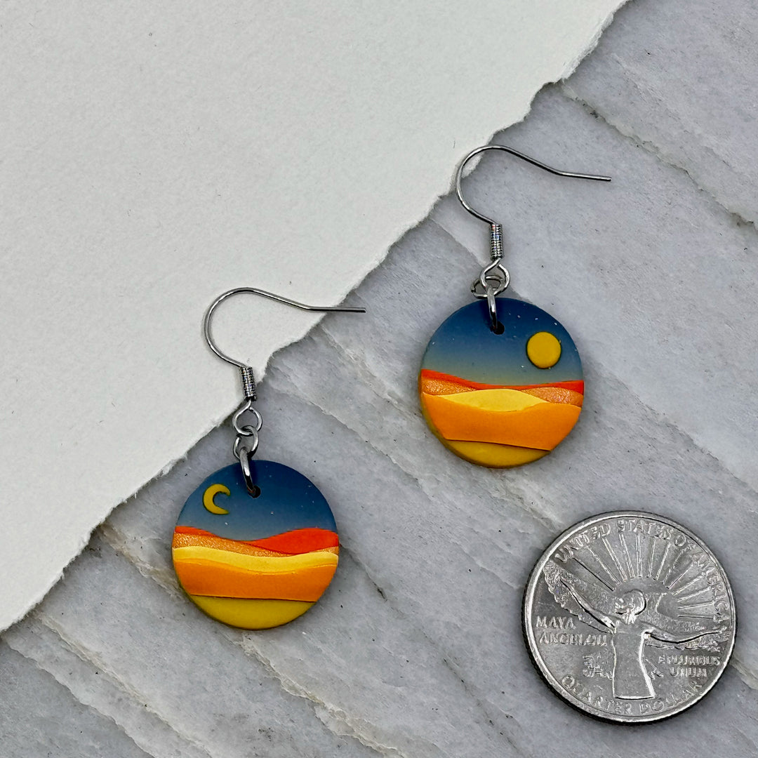 Pair of La Petite Rose's Big Sky Montana Sun Moon Landscape Clay Earrings (blue), with scale