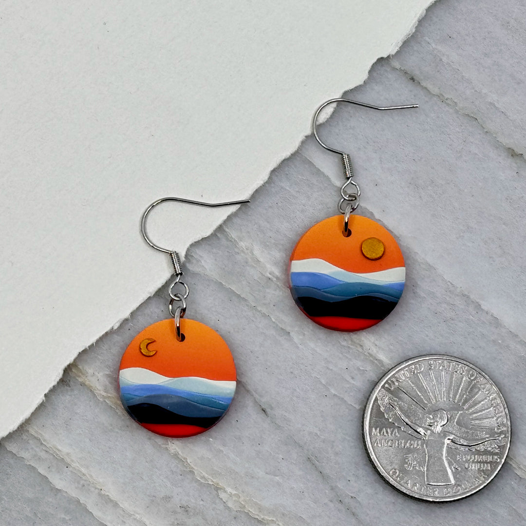 Pair of La Petite Rose's Big Sky Montana Sun Moon Landscape Clay Earrings (orange), with scale