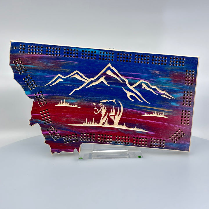Knotty Pine Woodworks Montana Bear Cribbage Board (sunset tones with natural wood accents, front)--this made in Montana wood cribbage board is in the shape of Montana with sunset colors, and features a bear and mountain peaks engraved in the front.