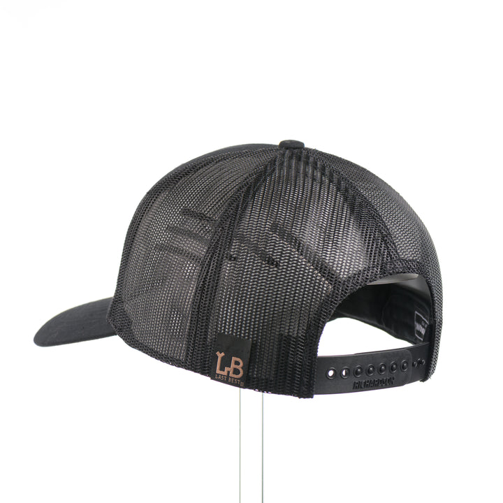 The back of an all black Richardson trucker hat with a black leather trout rectangle patch thick stitched on with black thread—handmade in Montana, USA by Last Best Supply Co.