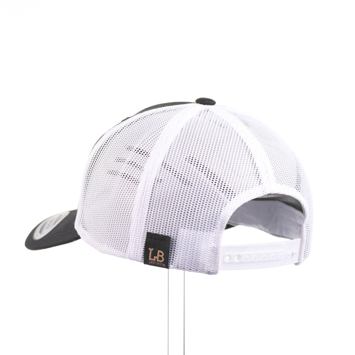 The back of a Sport-Tek Black & White Trucker Hat featuring a flexwood patch cut into the shape of a brown trout and etched with detail—handmade in Montana, USA by Last Best Supply Co.