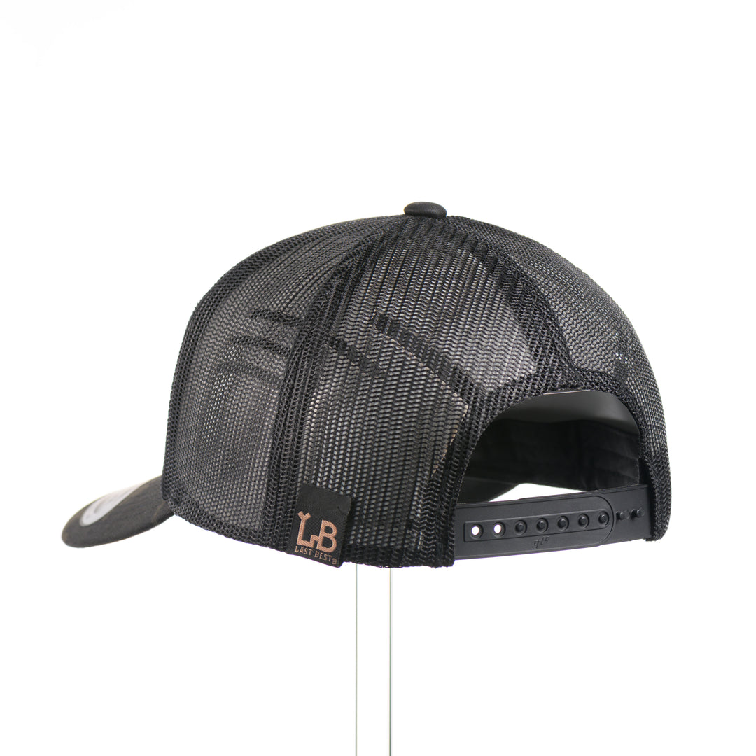 The back of a dark multicam trucker hat with a flexwood steer skull patch, handmade in Montana USA by Last Best Supply Co.