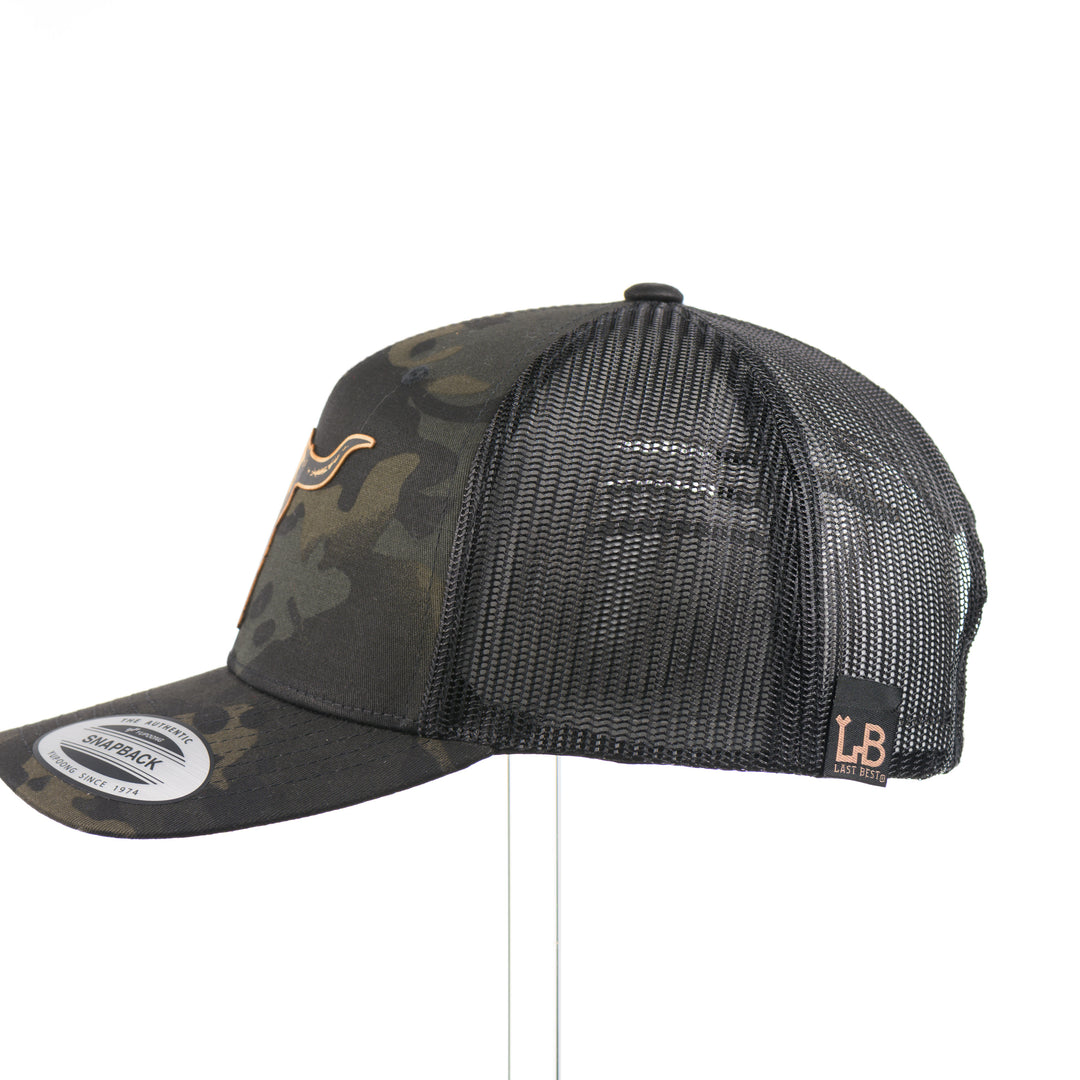 The side of a dark multicam trucker hat with a flexwood steer skull patch, handmade in Montana USA by Last Best Supply Co.