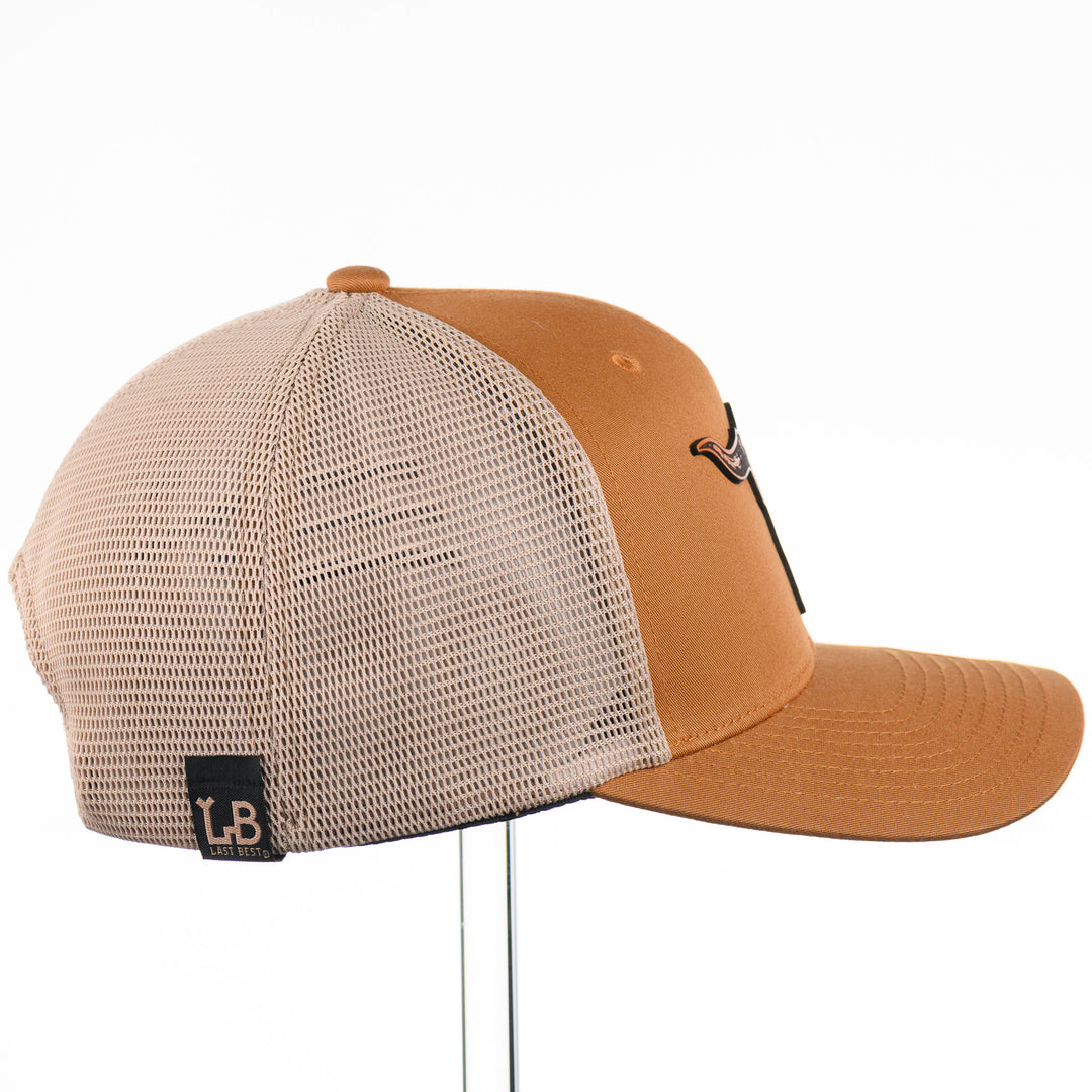 Etched Leather Bull Skull Patch Flexfit Trucker Hat, featuring a real leather patch cut into the shape of a steer skull and etched with detail, securely attached to a caramel and khaki trucker hat—handmade in Montana, USA by Last Best Supply Co.