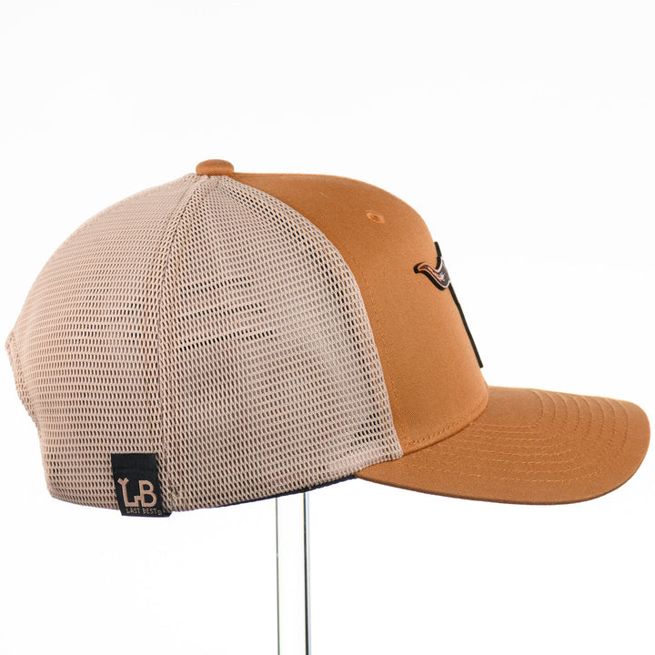 Etched Leather Bull Skull Patch Flexfit Trucker Hat, featuring a real leather patch cut into the shape of a steer skull and etched with detail, securely attached to a caramel and khaki trucker hat—handmade in Montana, USA by Last Best Supply Co.