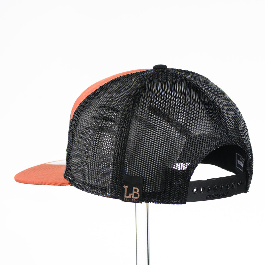 Etched Leather Chinook Salmon Patch Flat Bill Trucker Hat, featuring a real leather patch cut into the shape of a Chinook Salmon and etched with detail, securely attached to an orange and grey trucker hat—handmade in Montana, USA by Last Best Supply Co.