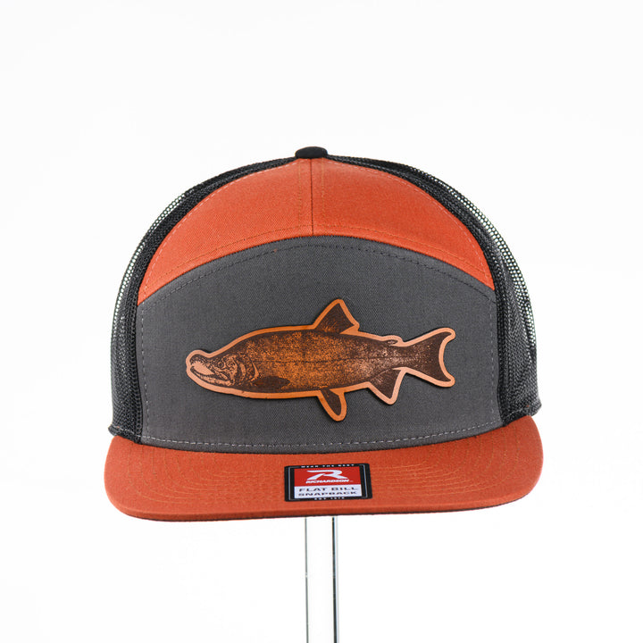 Etched Leather Chinook Salmon Patch Flat Bill Trucker Hat, featuring a real leather patch cut into the shape of a Chinook Salmon and etched with detail, securely attached to an orange and grey trucker hat—handmade in Montana, USA by Last Best Supply Co.