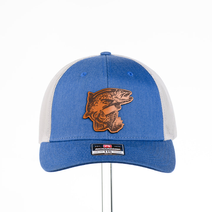 Etched Leather Fish Trucker Hat, featuring a real leather patch cut into the shape of a fish and etched with detail, securely attached to a blue and white trucker hat—handmade in Montana, USA by Last Best Supply Co.