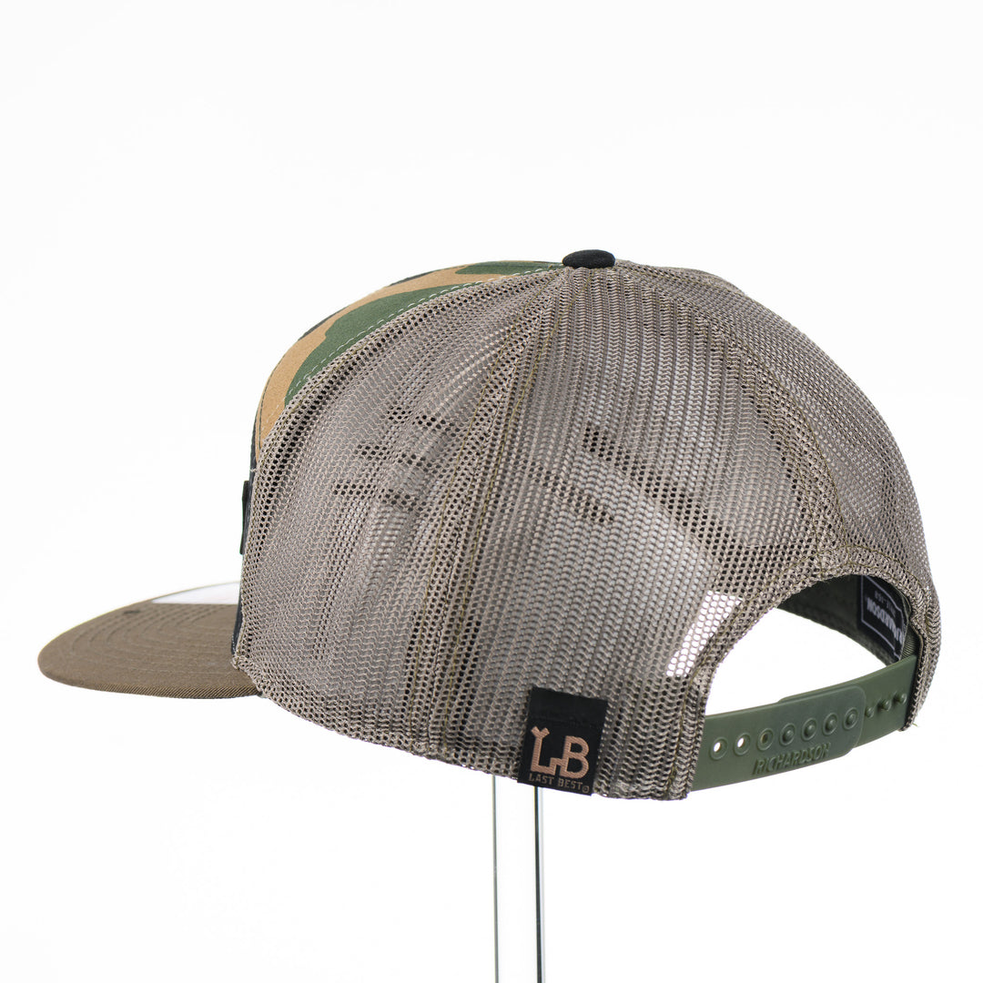 Etched Leather Sturgeon Patch on a Camo Tri-Colored Flat Bill Trucker Hat, featuring a real leather patch cut into the shape of a Sturgeon and etched with detail, securely attached to a Camo Tri-Colored flat bill trucker hat—handmade in Montana, USA by Last Best Supply Co.