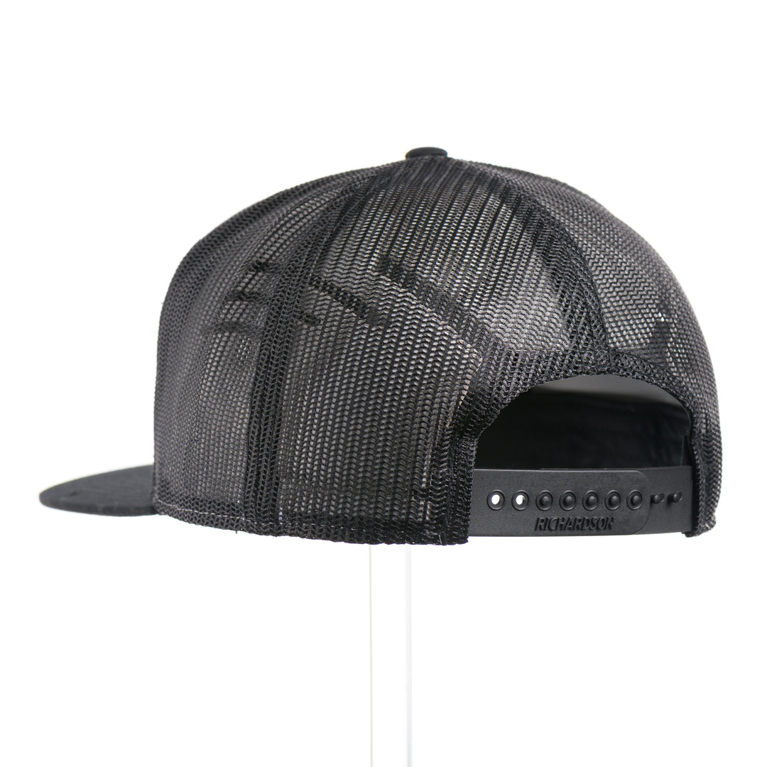 The back of a Walnut Wood Chinook Salmon American Flag Flat Bill Trucker Cap, featuring a real walnut wood veneer patch precision-cut into a hexagon, etched with an American flag with a Chinook salmon cut-out, laminated to a hexagonal black anodized aluminum plate, and riveted to a heather gray and black Richardson 168 flat bill trucker hat—handmade in Montana, USA by Last Best Supply Co.