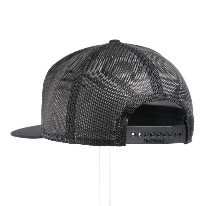 The back of a Walnut Wood Chinook Salmon American Flag Flat Bill Trucker Cap, featuring a real walnut wood veneer patch precision-cut into a hexagon, etched with an American flag with a Chinook salmon cut-out, laminated to a hexagonal black anodized aluminum plate, and riveted to a heather gray and black Richardson 168 flat bill trucker hat—handmade in Montana, USA by Last Best Supply Co.