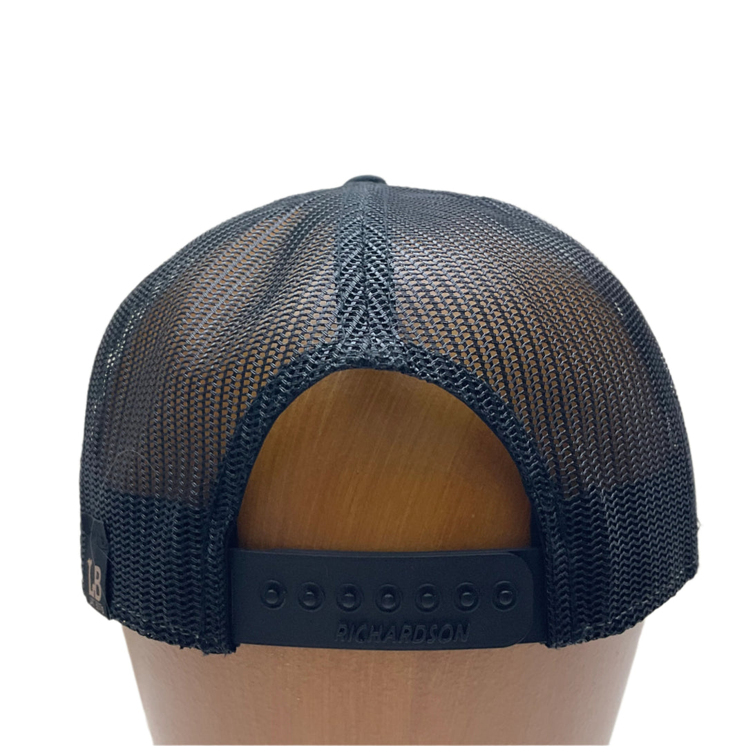 Back of a Hex Bear MT Wood Patch Richardson Flat Bill Hat, featuring a hexagonal, real wood veneer patch etched with a grizzly bear and the letters “MT”, laminated to a black anodized metal plate, and then riveted to heather gray and black Richardson 168 seven-panel flat bill trucker hat—handmade in Montana, USA by Last Best Supply Co.