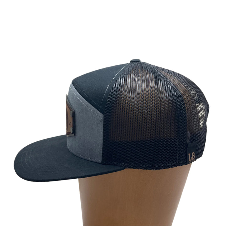 Side of a Hex Bear MT Wood Patch Richardson Flat Bill Hat, featuring a hexagonal, real wood veneer patch etched with a grizzly bear and the letters “MT”, laminated to a black anodized metal plate, and then riveted to heather gray and black Richardson 168 seven-panel flat bill trucker hat—handmade in Montana, USA by Last Best Supply Co.