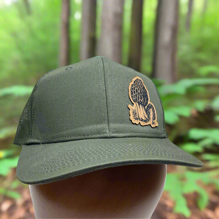Front of a Morel Flexwood Patch & Olive Green Trucker Hat, featuring a Flexwood patch cut into the shape of a morel mushroom, etched with fine details, and securely attached to a forest green mesh back trucker hat—handmade in Montana, USA by Last Best Supply Co.