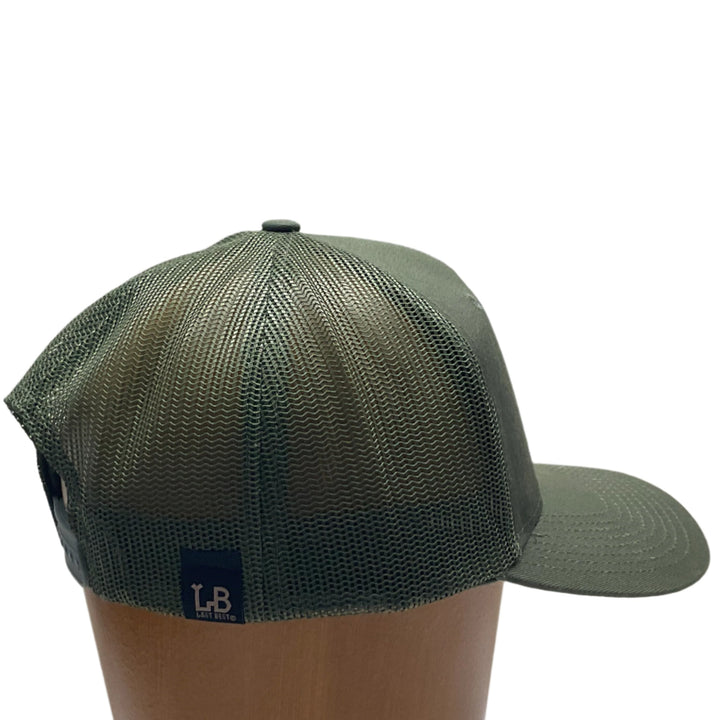 Side view of a Morel Flexwood Patch & Olive Green Trucker Hat, featuring a Flexwood patch cut into the shape of a morel mushroom, etched with fine details, and securely attached to a forest green mesh back trucker hat—handmade in Montana, USA by Last Best Supply Co.