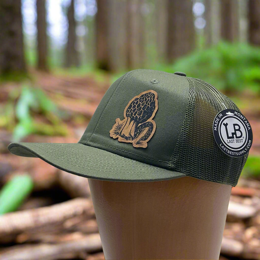 Side view of a Morel Flexwood Patch & Olive Green Trucker Hat, featuring a Flexwood patch cut into the shape of a morel mushroom, etched with fine details, and securely attached to a forest green mesh back trucker hat—handmade in Montana, USA by Last Best Supply Co.