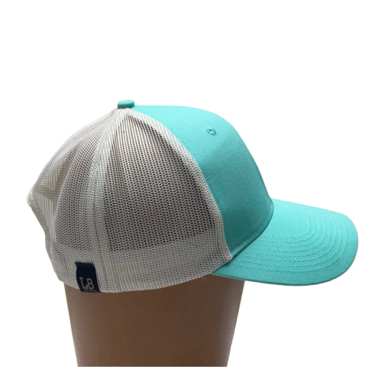 Premium Leather Montana Bear on Low Profile Teal Trucker Hat, featuring a blue hand-dyed leather patch cut in the shape of the state of Montana with a grizzly bear cut-out, heat pressed to the structured front of a teal and white  trucker hat—handmade in Montana, USA by Last Best Supply Co.