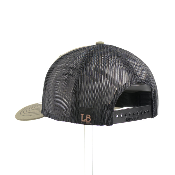 The back of a loden green and black mesh Richardson trucker hat with an etched walnut wood American flag and bison cut out on a black metal patch—handmade in Montana, USA by Last Best Supply Co.