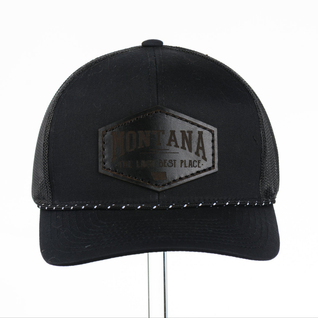 Black trucker cap with Montana The Last Best Place Leather Patch logo on a white background
