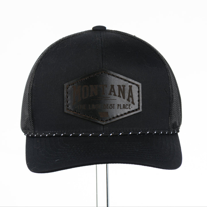 Black trucker cap with Montana The Last Best Place Leather Patch logo on a white background