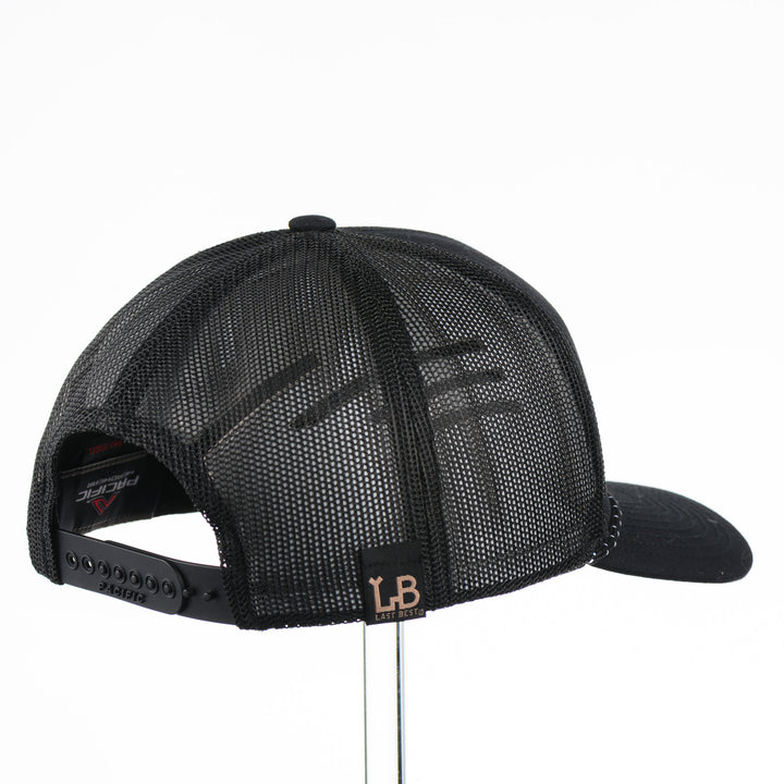 Back of a black mesh trucker hat with a black leather patch that says Montana The Last Best Place