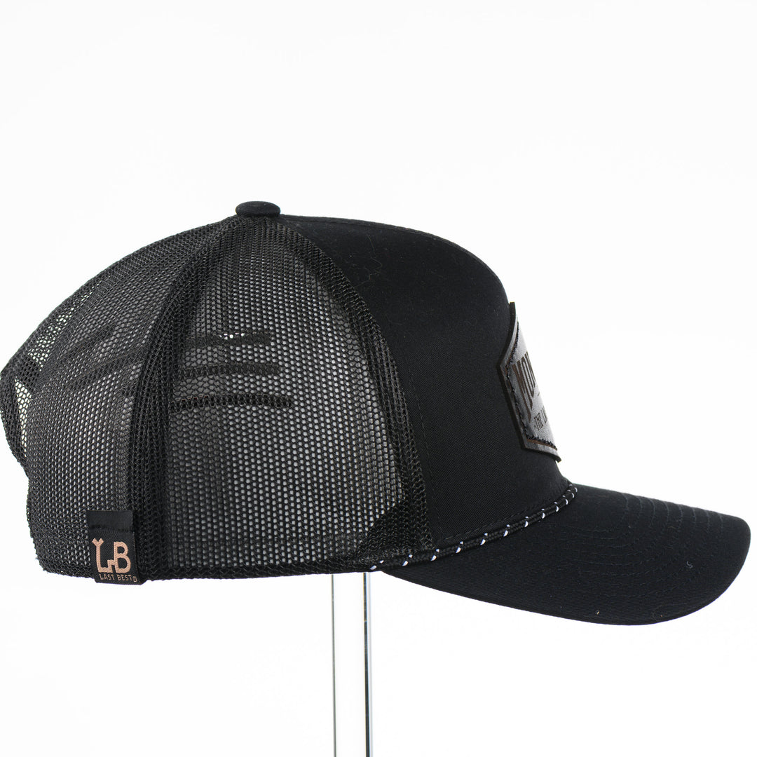 Black trucker cap side view with a black leather patch that says Montana The Last Best Place