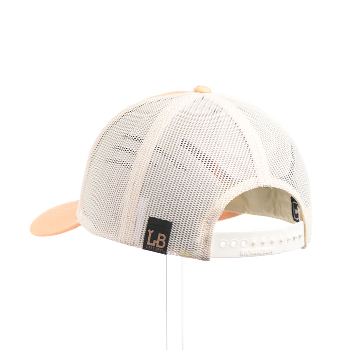 The back of a Cherry Wood Grizzly Bear w/ Paisley Peach & Cream Trucker Hat, featuring a real cherry wood veneer patch etched with a paisley design around a bear silhouette cut-out, laminated to a black anodized aluminum plate, and riveted to a peaches-and-cream Richardson 115 low-profile trucker hat—handmade in Montana, USA by Last Best Supply Co.