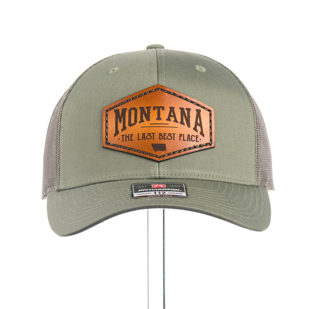 Green trucker cap with leather patch featuring 'Montana The Last Best Place' on a white background