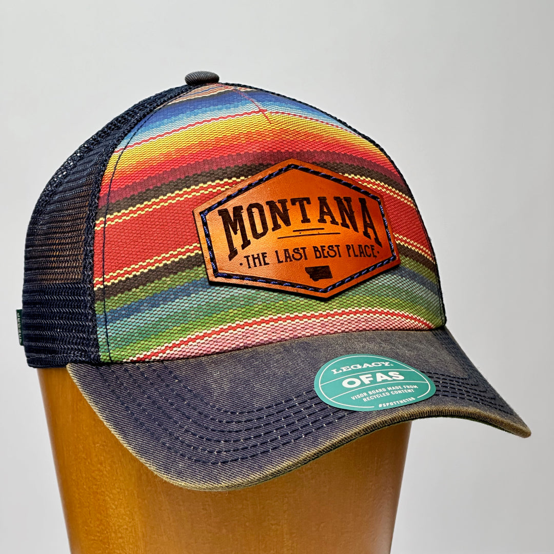 A poncho printed trucker hat with a thick leather patch that says Montana, The Last Best Place.