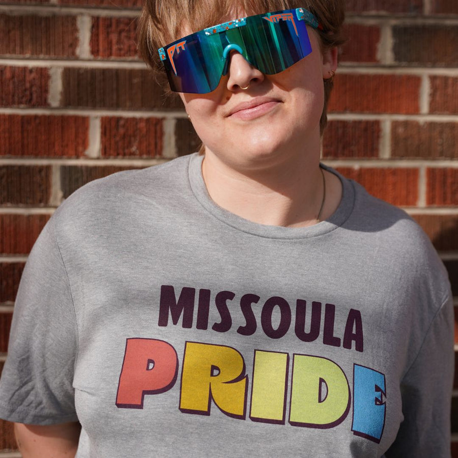 Grey all-gender / unisex t-shirt featuring the Missoula PRIDE logo made in Montana, USA; a portion of sales are donated to the Missoula Pride fundraiser.