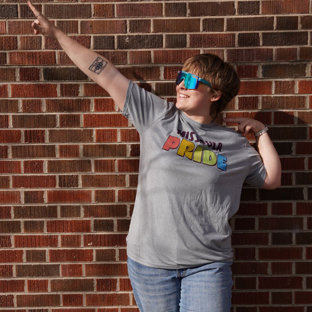 Grey all-gender / unisex t-shirt featuring the Missoula PRIDE logo made in Montana, USA; a portion of sales are donated to the Missoula Pride fundraiser.