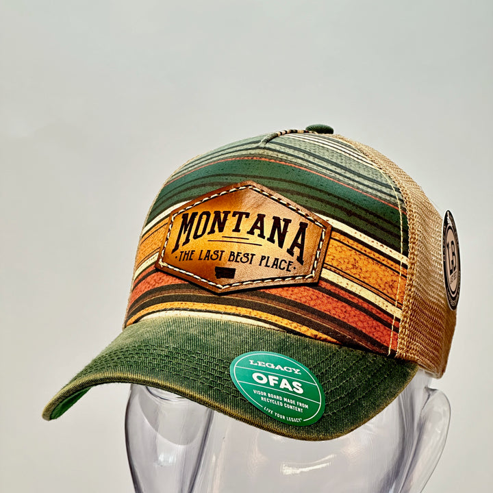A side view of a green lined printed Legacy trucker hat with a thick leather patch that says Montana, The Last Best Place.