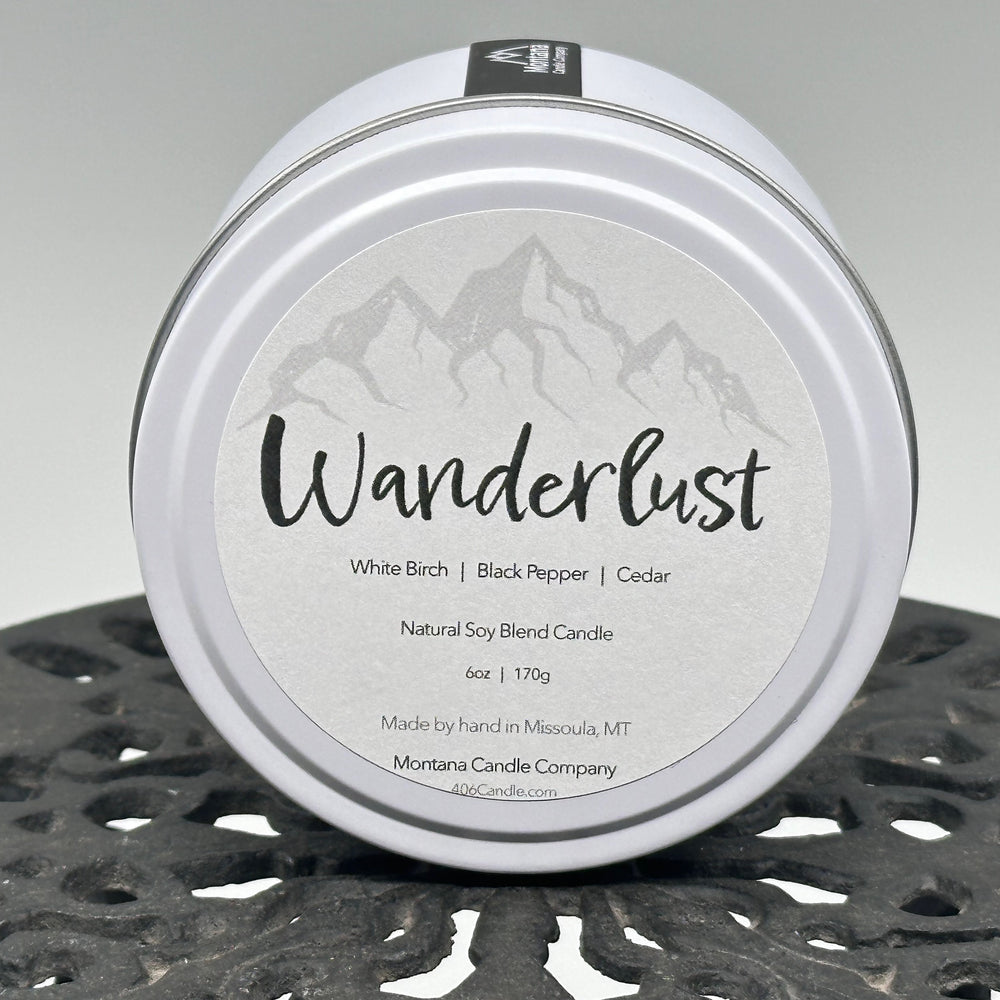Wanderlust Candle soy blend candle handmade in Missoula, Montana by Montana Candle Company, scented with a white birch, black pepper, and cedar, 6 oz. tin