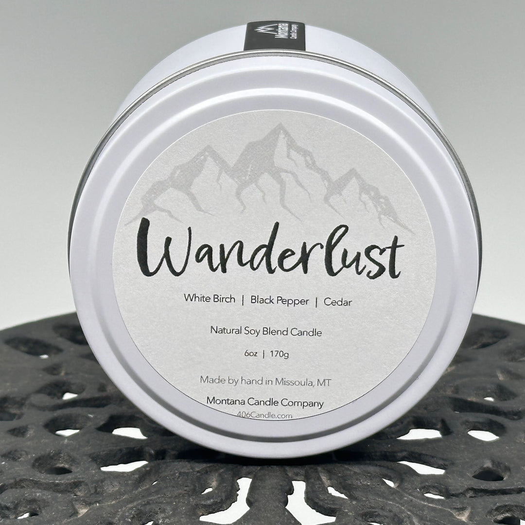 Wanderlust Candle soy blend candle handmade in Missoula, Montana by Montana Candle Company, scented with a white birch, black pepper, and cedar, 6 oz. tin