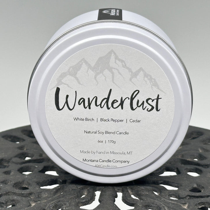 Wanderlust Candle soy blend candle handmade in Missoula, Montana by Montana Candle Company, scented with a white birch, black pepper, and cedar, 6 oz. tin
