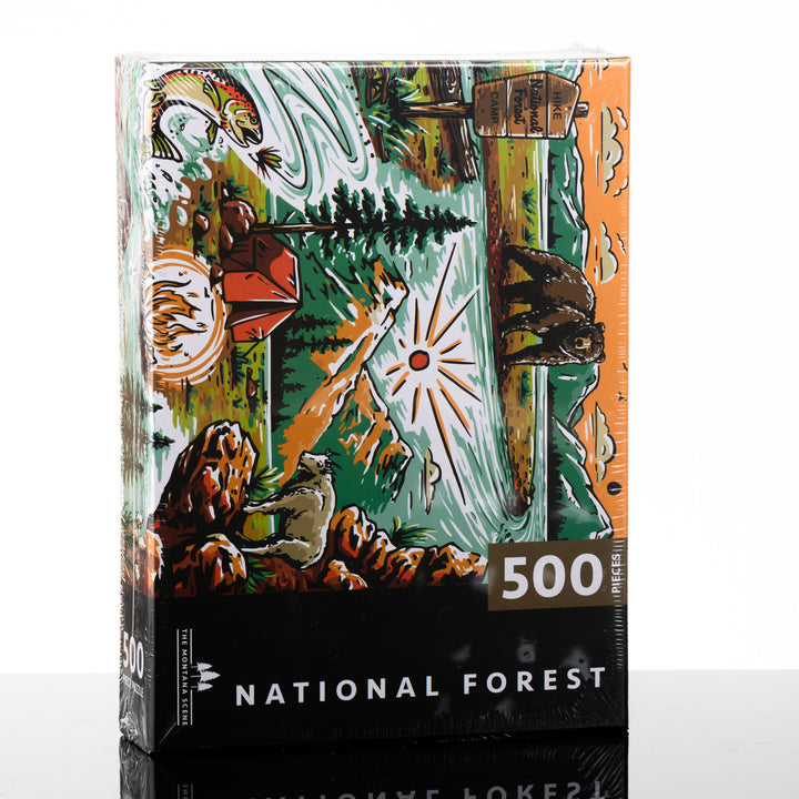 Hand drawn, Montana-made 500 piece puzzle by the Montana Scene--named National Forest-- featuring a bear, national forest sign, fly fishing, tent and mountain goat; image depicts the front of the puzzle box.