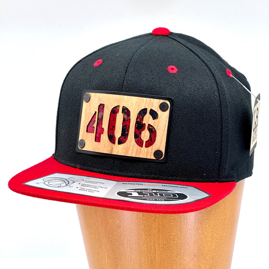 A flex fit, black and red flat bill hat with a wood and metal patch featuring 406, for the Montana area code, and red copper inlay.