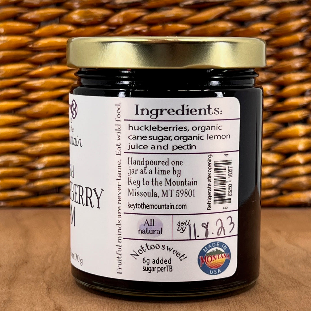 A 6oz jar of Key to the Mountain's, Montana handmade Wild Huckleberry Jam ingredients list: huckleberries, organic cane sugar, organic lemon juice, and pectin