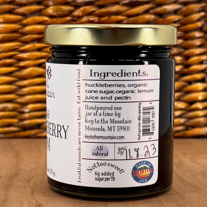 A 6oz jar of Key to the Mountain's, Montana handmade Wild Huckleberry Jam ingredients list: huckleberries, organic cane sugar, organic lemon juice, and pectin