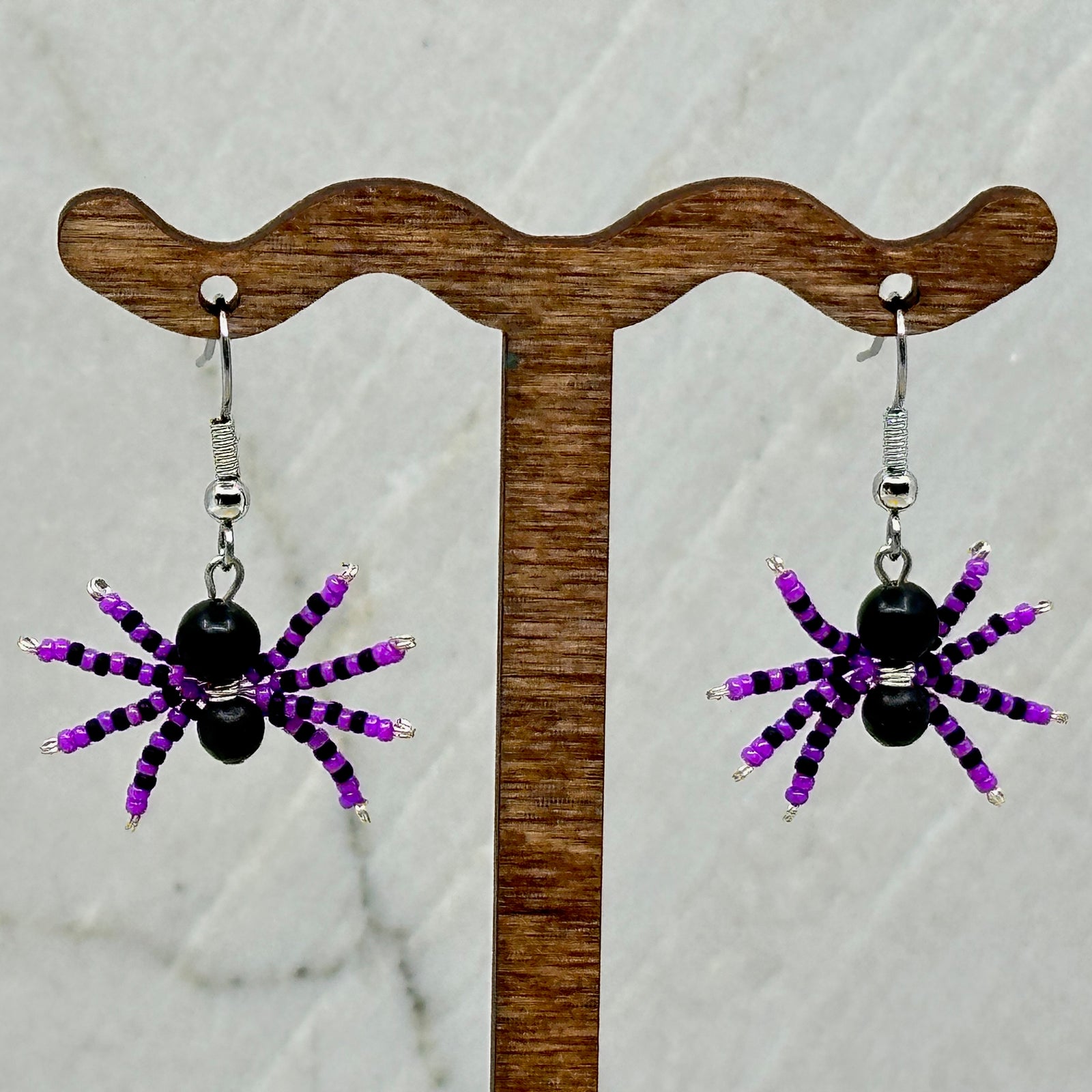 Pair of purple and black Spider Beaded Earrings with Stainless Steel Wires, handmade in Montana USA by Aurum Shimmer, hanging