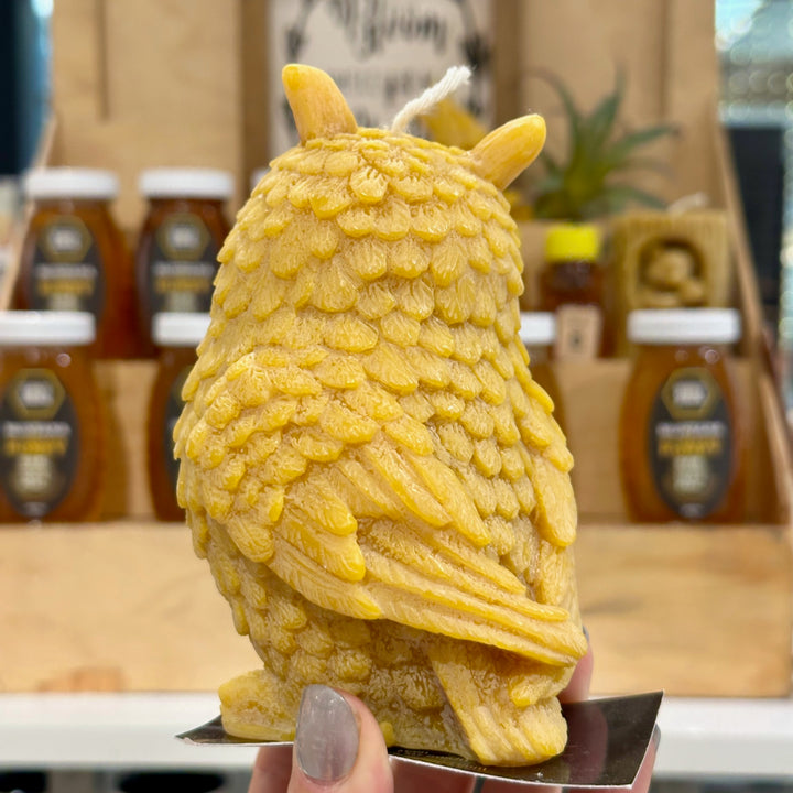 The back of a golden yellow owl candle made of 100% Montana beeswax