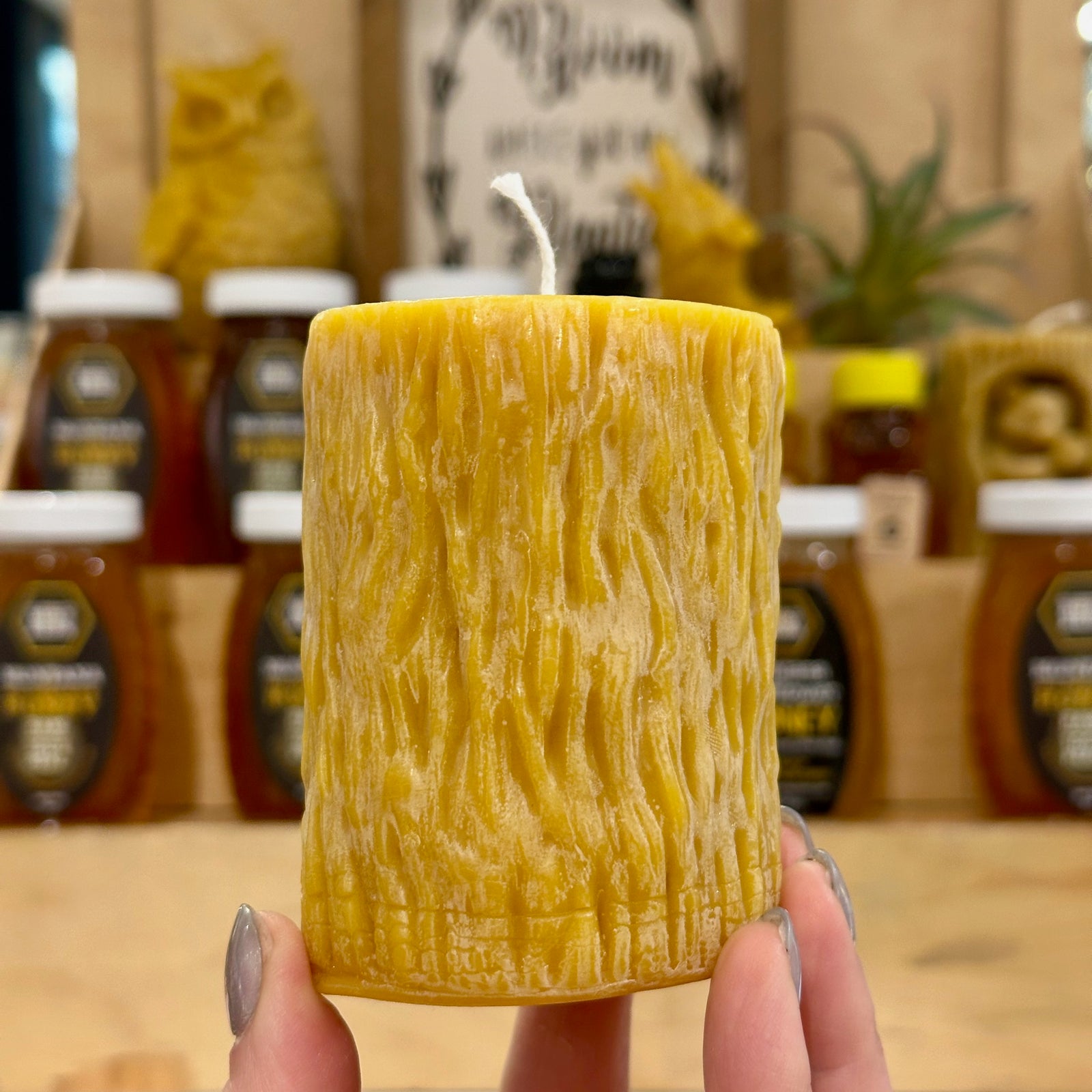 The back of a 100% Montana beeswax candle showing the textured back of a tree trunk shaped candle
